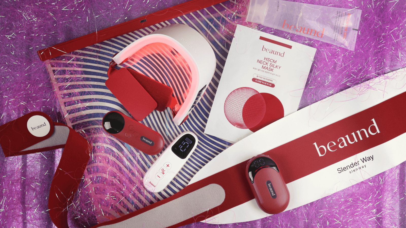 Färgstark flatlay-bild med Beauds skönhets- och wellnessprodukter, inklusive LED-enhet, neck mask och Slimder Way-produkter i röd design mot glittrig lila bakgrund.