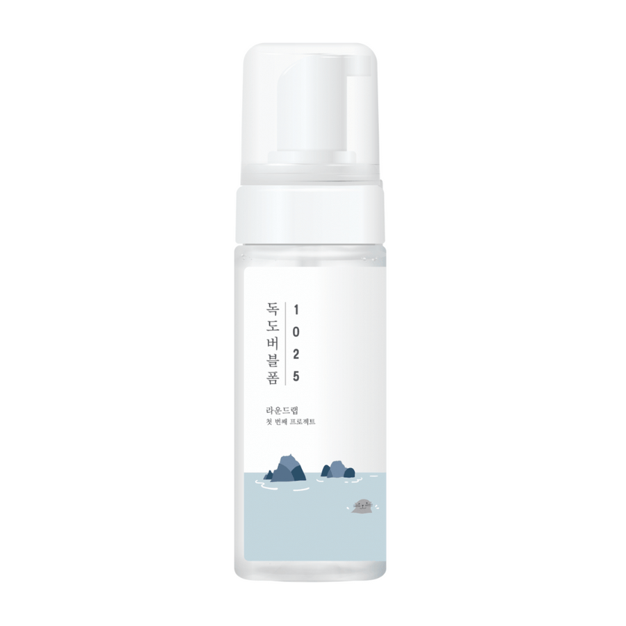 1025 Dokdo Bubble Foam" är en ansiktsrengöringsprodukt från ROUND LAB, förpackad i en vit pumpflaska med enkel och ren design, prydd med text och minimalistiska illustrationer av havslandskap. 