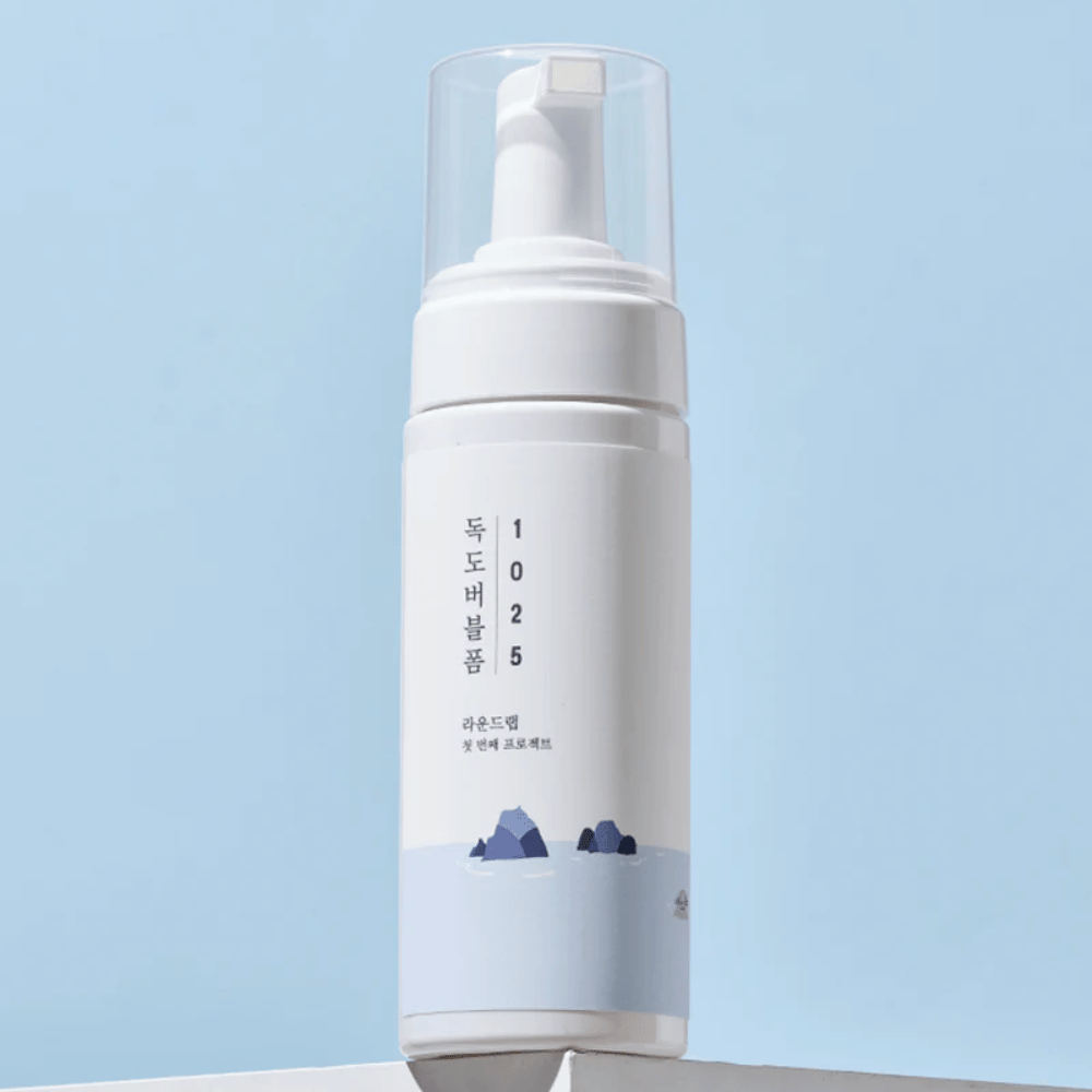  Produkten är en "1025 Dokdo Bubble Foam" från ROUND LAB, förpackad i en vit pumpflaska med minimalistisk design. Den är avsedd för djuprengöring av ansiktet utan irritation.