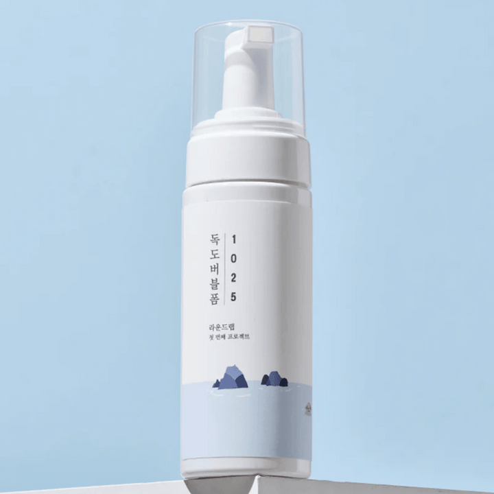  Produkten är en "1025 Dokdo Bubble Foam" från ROUND LAB, förpackad i en vit pumpflaska med minimalistisk design. Den är avsedd för djuprengöring av ansiktet utan irritation.