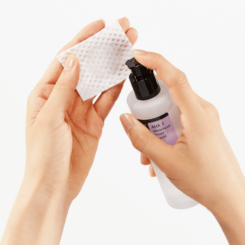 Applicering av COSRX AHA 7 Whitehead Power Liquid på bomullspad, exfolierande toner med AHA för att avlägsna döda hudceller och förbättra hudstruktur.
