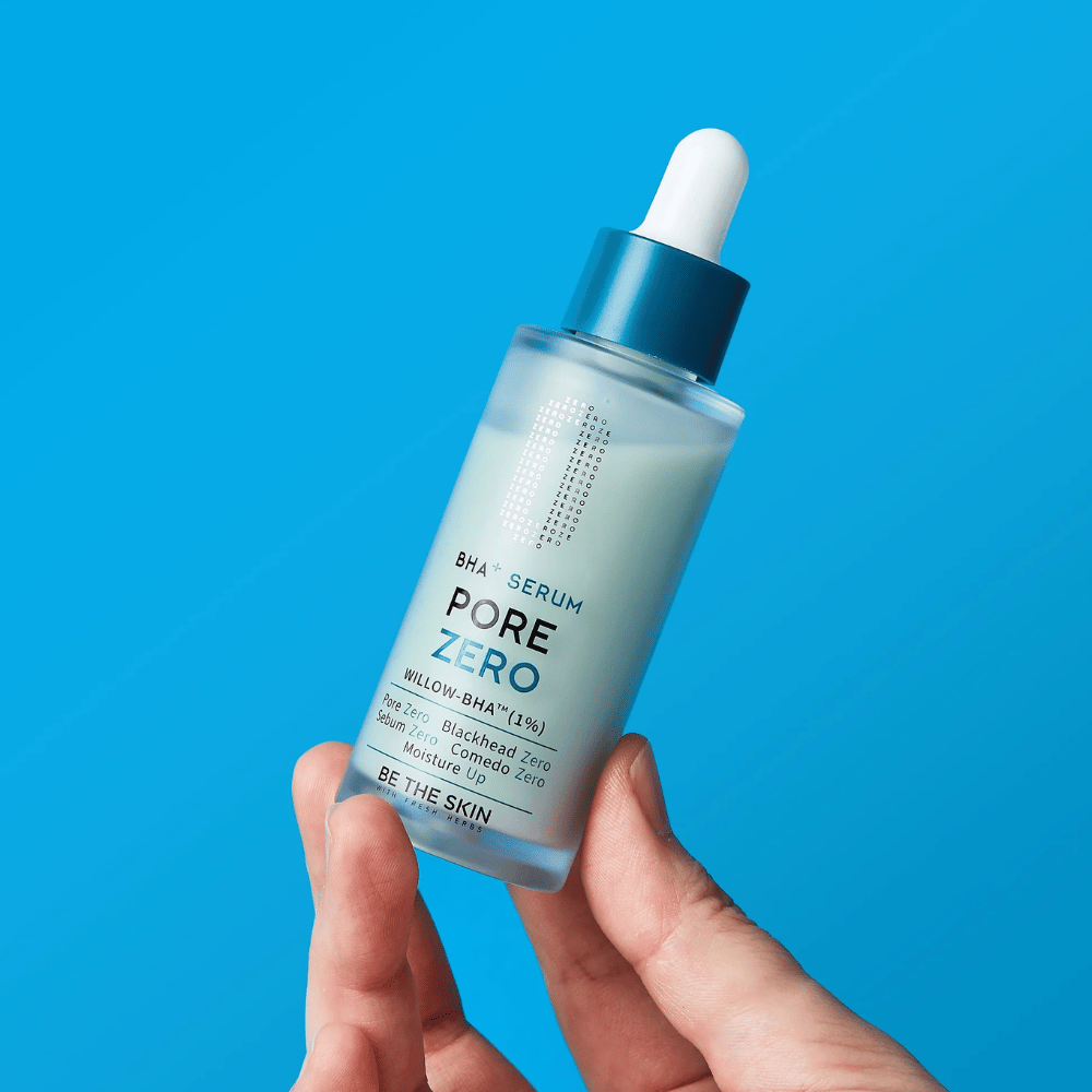 Be The Skin BHA+ Pore Zero Serum hålls i handen mot blå bakgrund