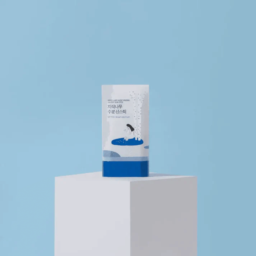 ROUND LAB Birch Juice Moisturizing Sun Stick SPF50+ står på piedestal mot blå bakgrund – återfuktande solskydd i stickformat