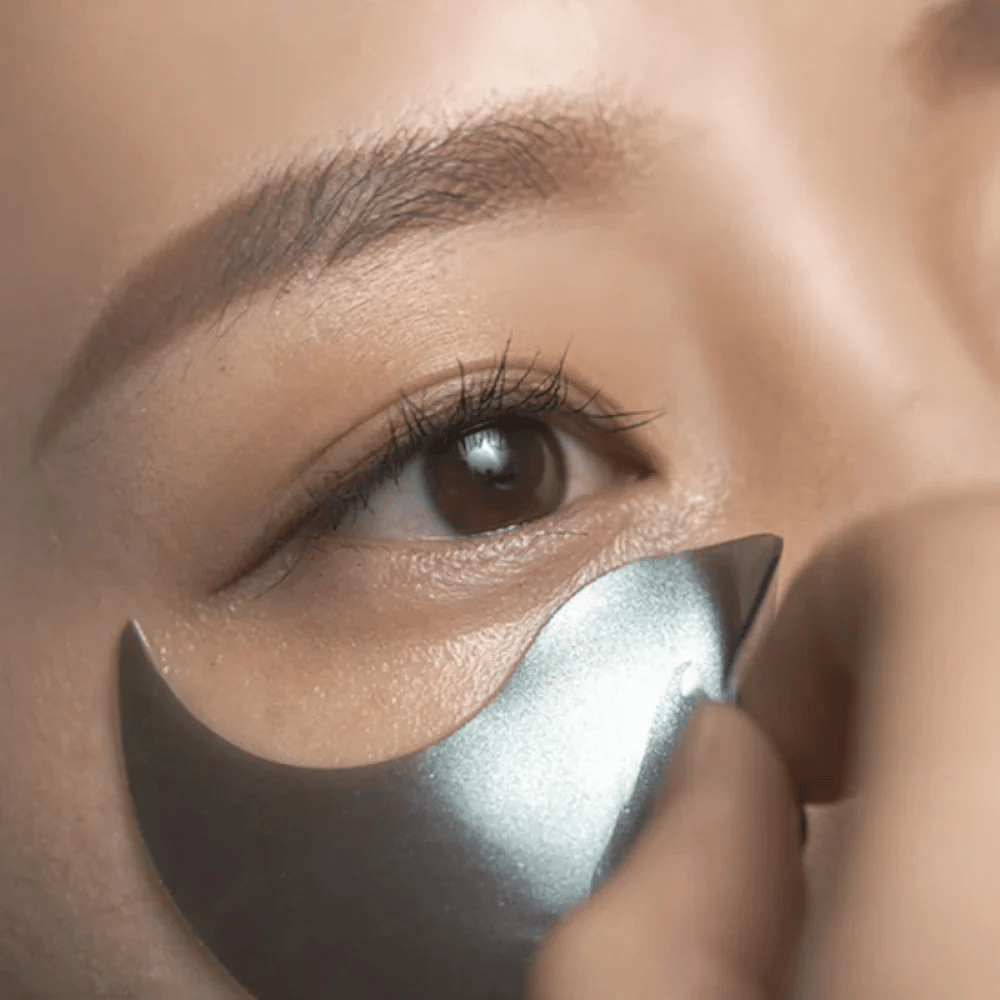 Detaljerad bild där en svart hydrogel eye patch appliceras under ögat. Bilden visar den täta passformen och den svalkande känslan runt ögonområdet.