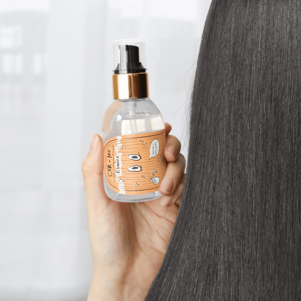 Person håller CER-100 Hair Essence bredvid långt, glansigt hår för att visa mjukhet och vård.