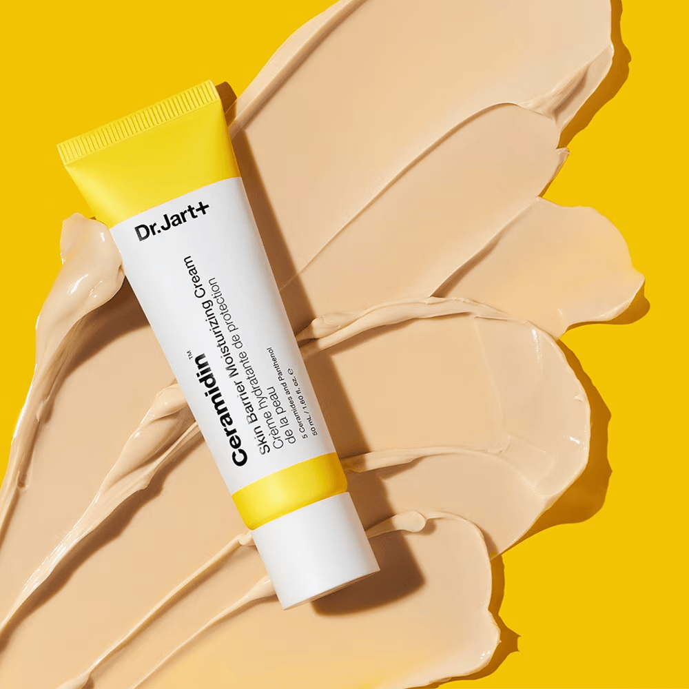 Tub med Dr. Jart+ Ceramidin Skin Barrier Moisturizing Cream mot en gul bakgrund med kräm utspridd.