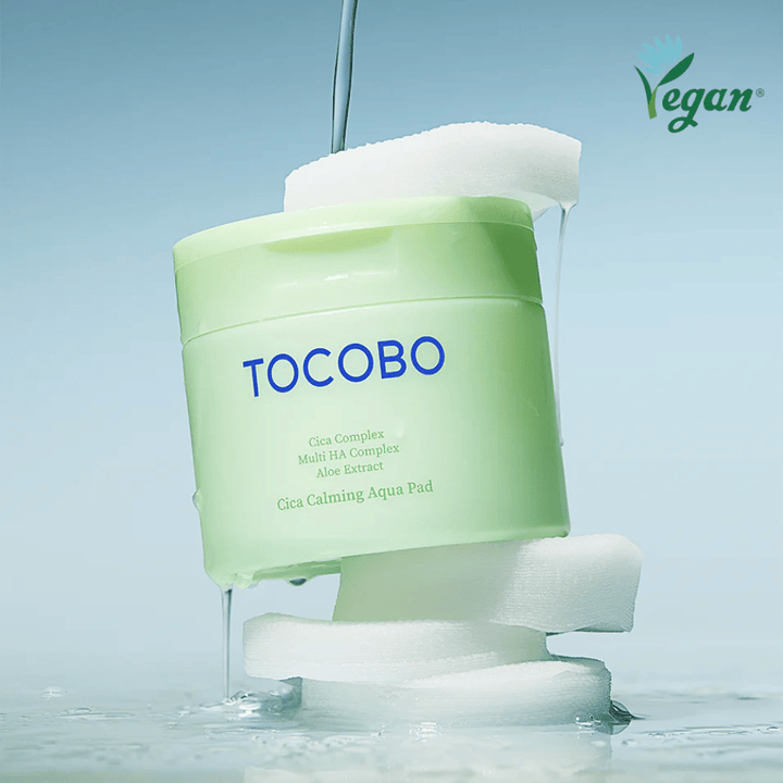 TOCOBO Cica Calming Aqua Pad placerad mellan toner pads med rinnande essence. Vegan-symbolen betonar produktens veganska formulering och hudvänliga profil.