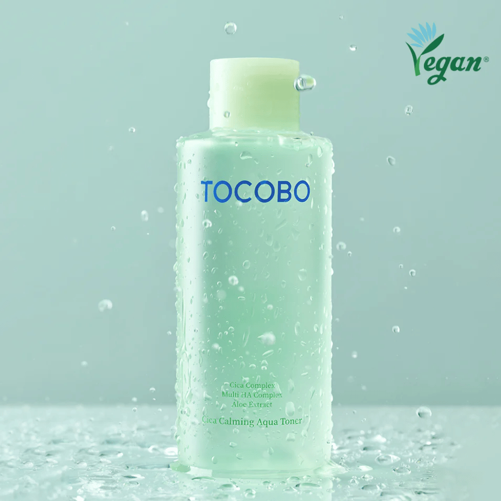 Produktbild av TOCOBO Cica Calming Aqua Toner omgiven av vattendroppar som lyfter fram tonerns återfuktande och lugnande egenskaper för känslig hud.