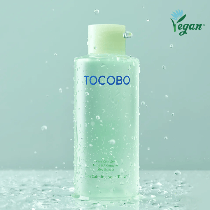 Produktbild av TOCOBO Cica Calming Aqua Toner omgiven av vattendroppar som lyfter fram tonerns återfuktande och lugnande egenskaper för känslig hud.