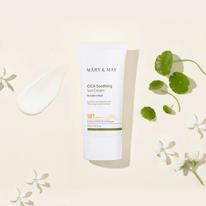 Mary&May CICA Soothing Sun Cream SPF50+ PA++++ presenterad tillsammans med en krämtextur, centella-blad och vita blommor. Bilden lyfter fram produktens lugnande egenskaper och fokus på känslig hud.