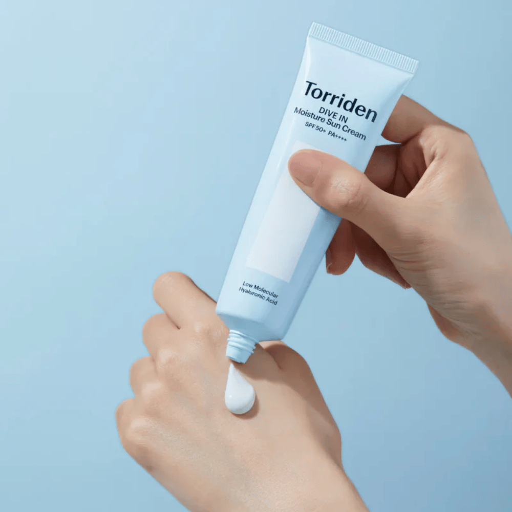Torriden DIVE-IN Moisture Sun Cream SPF50+ PA++++ appliceras på handen för att visa den återfuktande solkrämens lätta och krämiga konsistens.