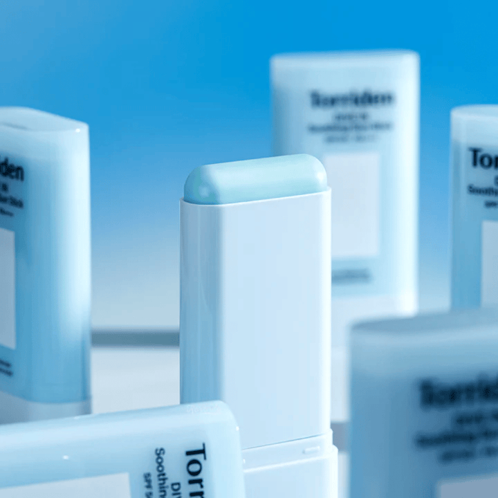 Närbild på Torriden DIVE IN Soothing Sun Stick som visar den mjuka solskyddsformulan i stickformat med flera produkter i bakgrunden.