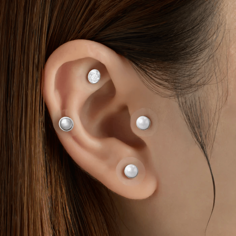 Närbild på ett öra med flera RETURNITY Ear Therapy Acupressure Patch applicerade på olika områden av örat för akupressur och stilren look.