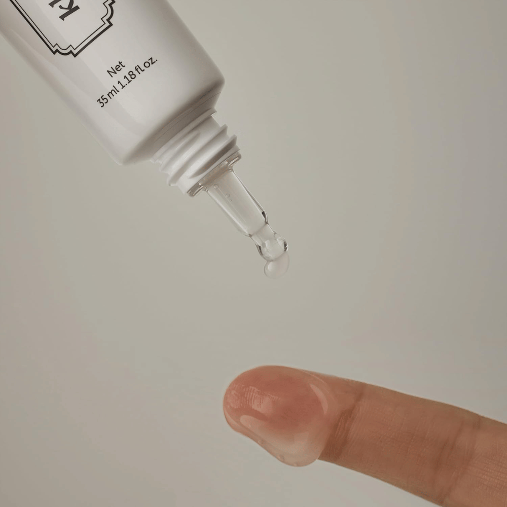 Detaljbild där en klar, lätt gel appliceras från den smala spetsen mot ett finger. Bilden illustrerar produktens transparenta, gelbaserade konsistens och den precisa appliceringen runt ögonområdet.
