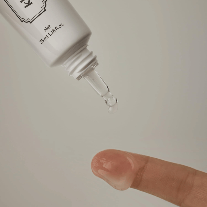 Detaljbild där en klar, lätt gel appliceras från den smala spetsen mot ett finger. Bilden illustrerar produktens transparenta, gelbaserade konsistens och den precisa appliceringen runt ögonområdet.