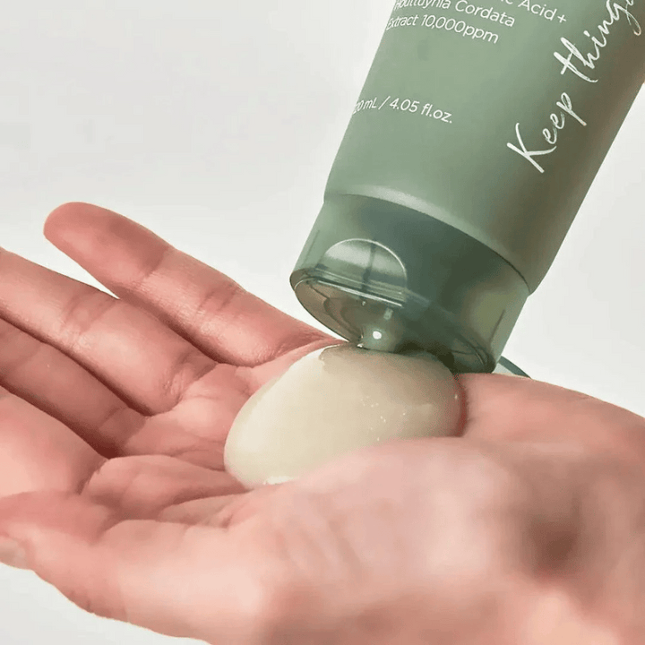 En hand håller en genomskinlig klump av Keep Cool Soothe Phyto Green Shower Cleansing Gel, pressad ur en grön tub.