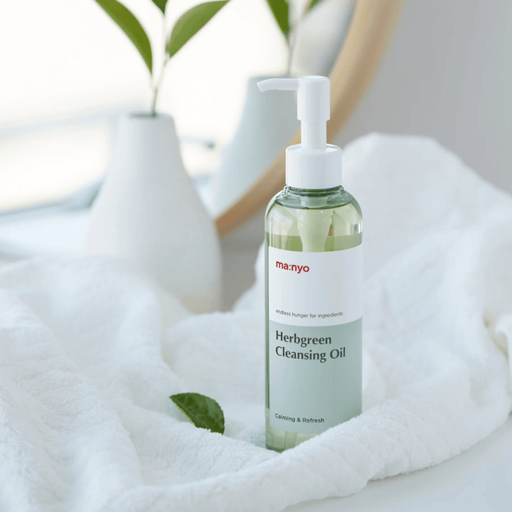 ma:nyo Herbgreen Cleansing Oil i pumpflaska placerad på vit handduk, lugnande rengöringsolja med örtbaserade ingredienser för skonsam ansiktsrengöring