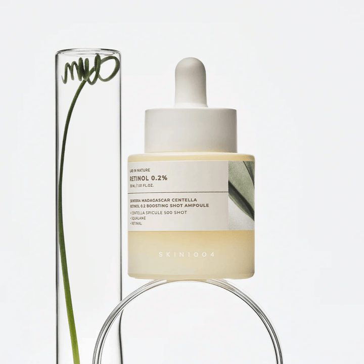 SKIN1004 Madagascar Centella Retinol 0.2 Boosting Shot Ampoule i livsstilsbild med botaniska element – ansiktsserum som stödjer hudens förnyelse och stärker hudbarriären.