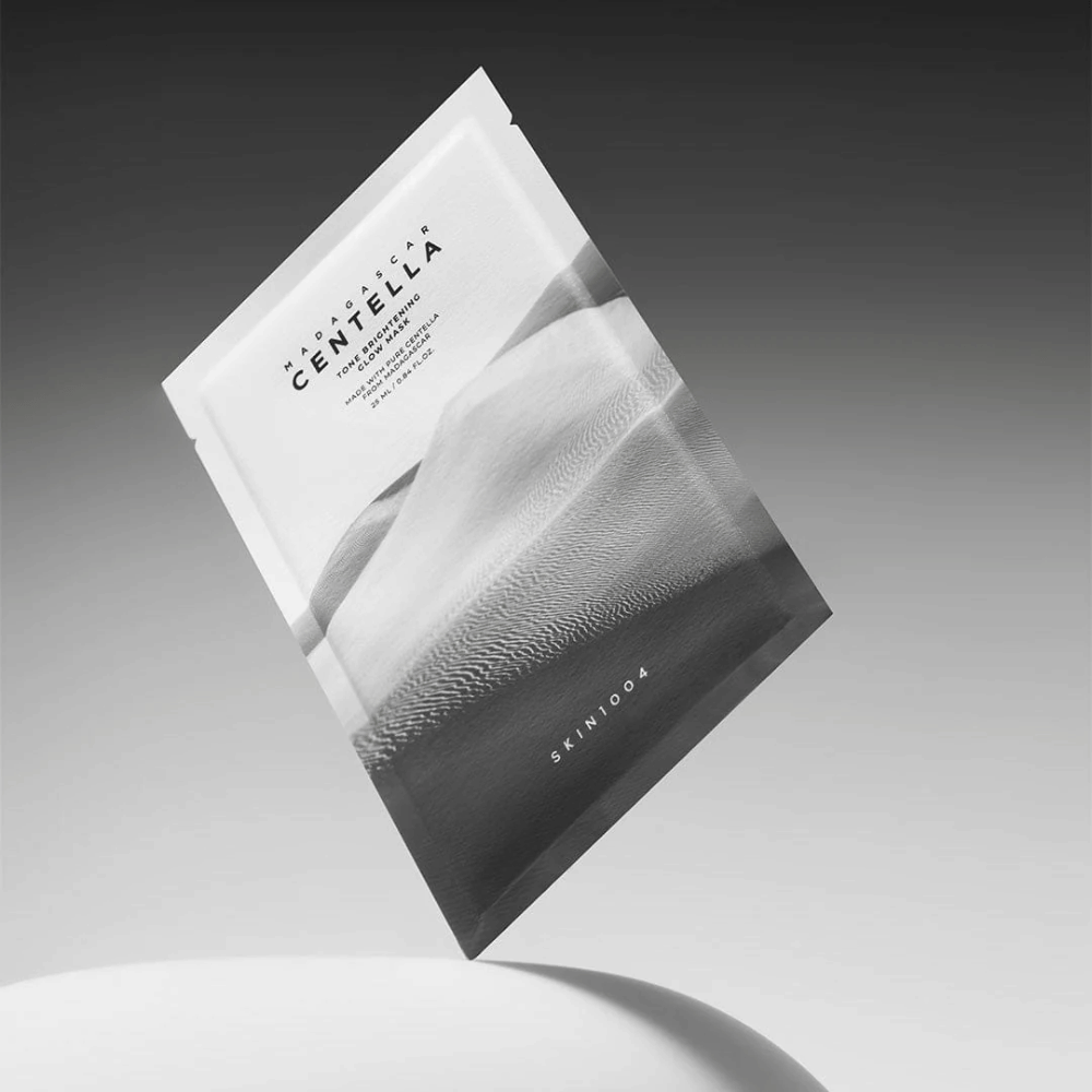 Sheet mask-förpackning från SKIN1004 svävande mot grå bakgrund med minimalistisk design.