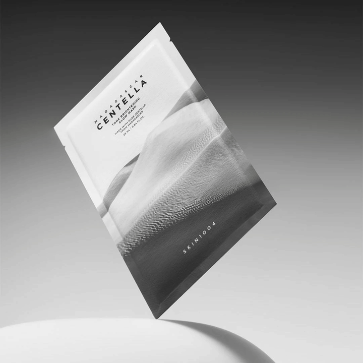 Sheet mask-förpackning från SKIN1004 svävande mot grå bakgrund med minimalistisk design.