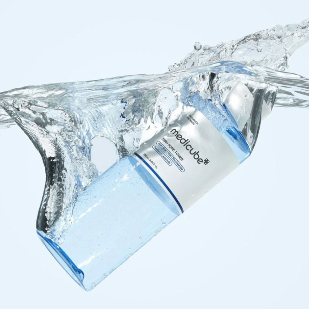 Medicube Zero Pore Toner 250 ml, exfolierande toner med AHA, BHA och PHA. Genomskinlig blå flaska omgiven av ett stort vattenstänk.