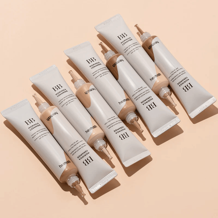 Flera tuber av Heimish Moringa Ceramide BB Cream arrangerade på ljus beige bakgrund. Bilden framhäver de olika nyanserna och produktens eleganta, minimalistiska förpackningsdesign.