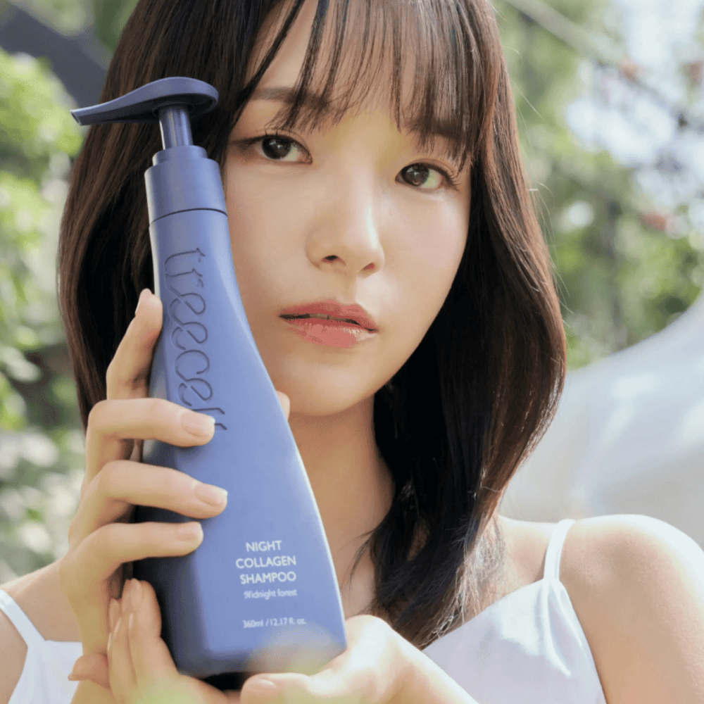 Kvinna håller upp Treecell Night Collagen Shampoo Midnight Forest i en naturlig miljö. Bilden förmedlar friskt hår, glans och premiumkänsla med fokus på hår- och hårbottenvård.