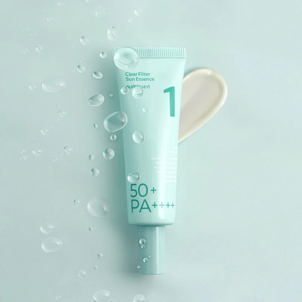 En ljusblå tub med No.1 Clear Filter Sun Essence SPF 50+ PA++++. Tuben är dekorerad med vattendroppar och en klick av produkten visas bredvid. Produkten är designad för att ge hög solskyddsfaktor och skydd mot UVA/UVB-strålar.