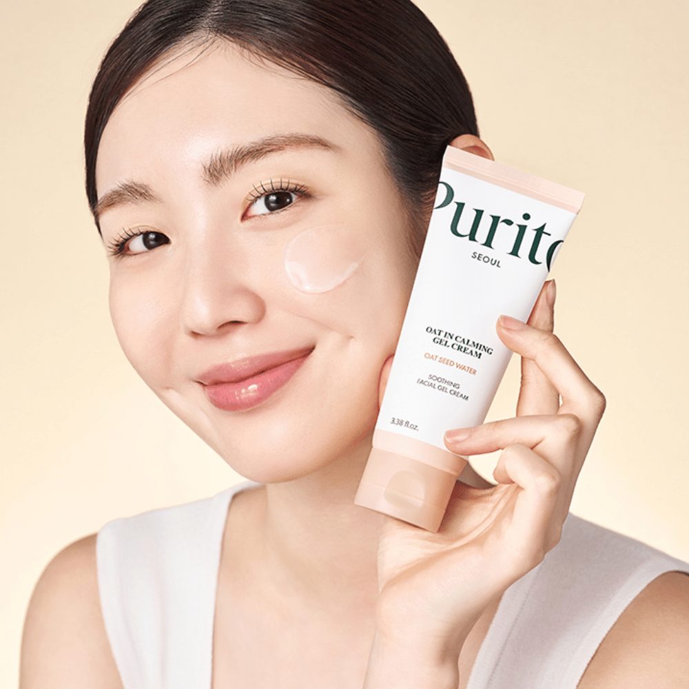 Kvinna applicerar Purito Oat-In Calming Gel Cream i ansiktet. Mild och återfuktande gelkräm för känslig och irriterad hud.