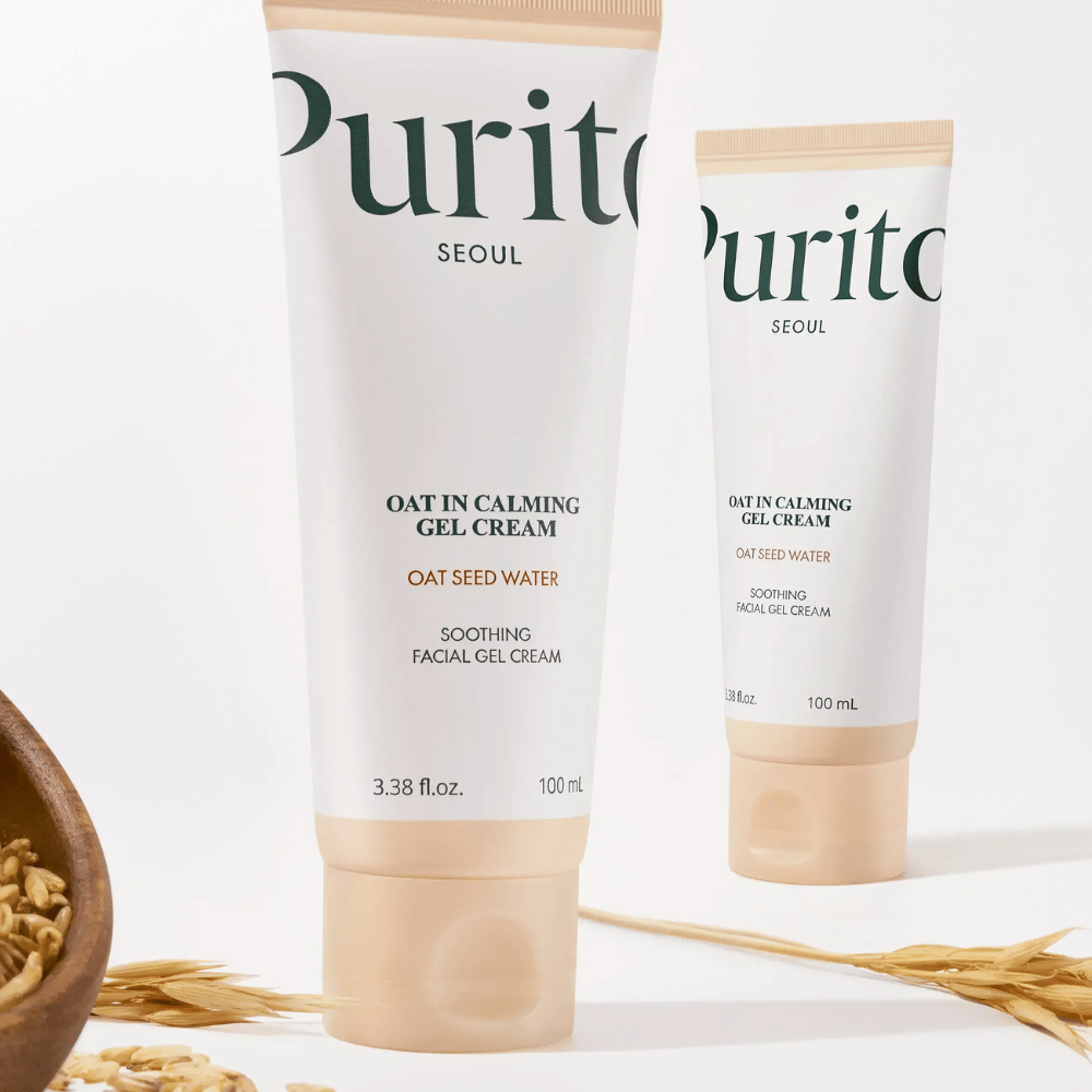 Purito Oat-In Calming Gel Cream i beige tub, placerad med havrekorn. Lugnar känslig hud med havrevatten och lätt geltextur.