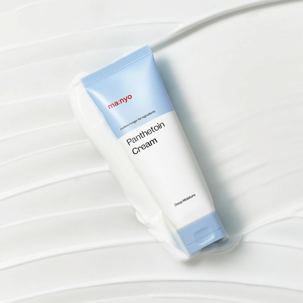2. Ma:nyo Panthetoin Cream – återfuktande ansiktskräm i vit och ljusblå tub omgiven av krämig textur på vit bakgrund