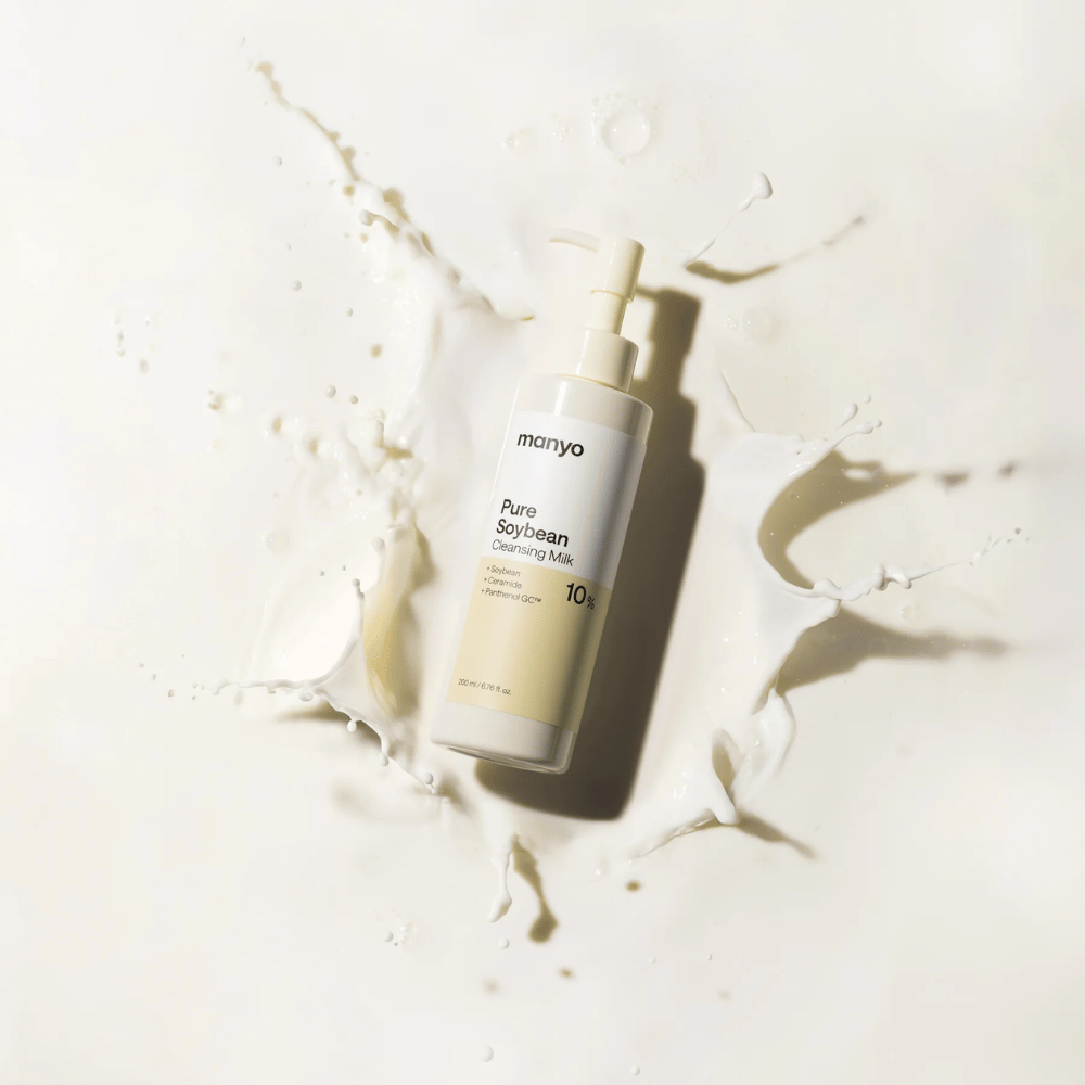 1. Ma:nyo Pure Soybean Cleansing Milk – mild rengöringsmjölk med soja i pumpflaska omgiven av mjölkstänk på ljus bakgrund