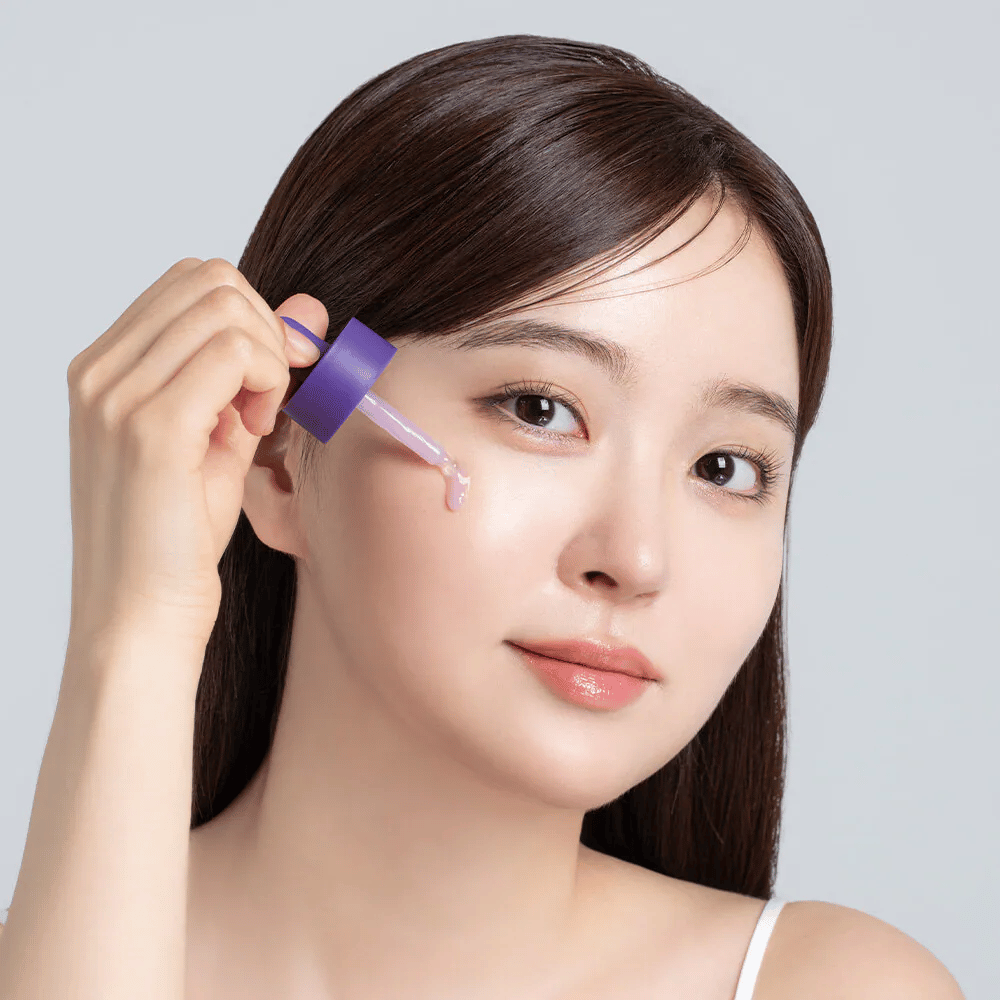 Applicering av Cellology Purple Carrot Pore Ampoule med pipett på ansiktet för porvård och jämnare hudtextur.