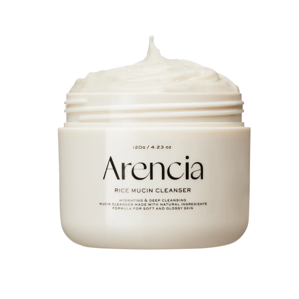 Produktbild på Arencia Rice Mucin Cleanser i en vit burk med krämig, vispad textur som sticker upp ur öppningen. Text på förpackningen betonar återfuktning och djuprengöring.