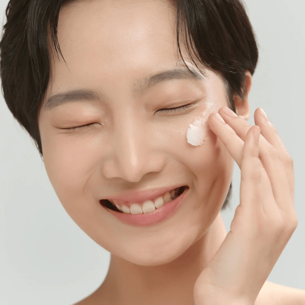 Modell med glowig hud applicerar Beauty of Joseon Radiance Cleansing Balm – koreansk rengöringsbalm som smälter bort smink och orenheter.