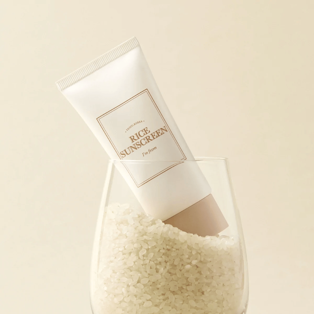 Tub med "I'm from" Rice Sunscreen, SPF50+ PA++++, placerad i ett glas med riskorn.