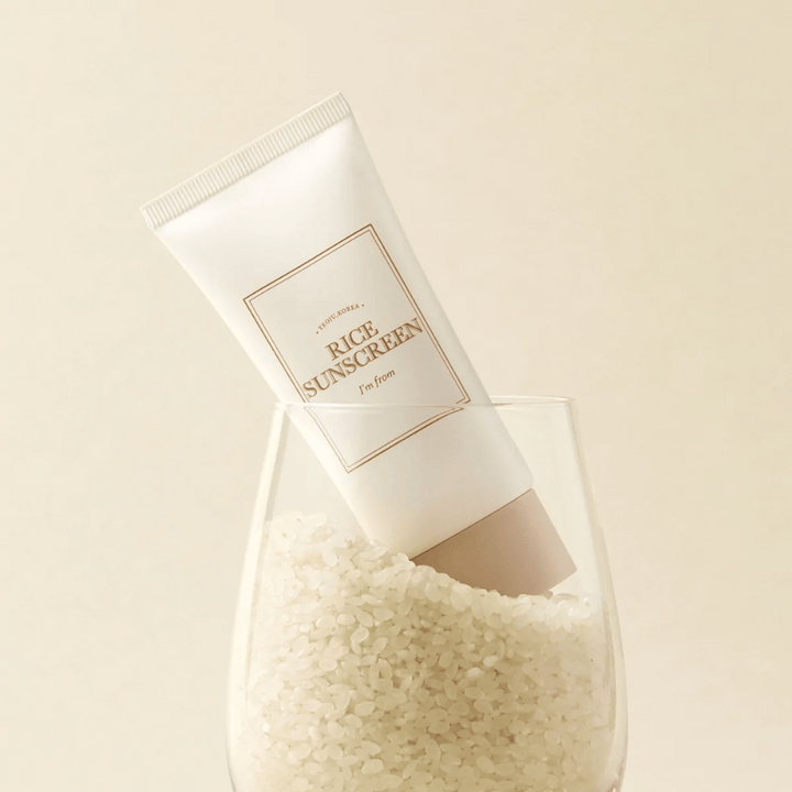 Tub med "I'm from" Rice Sunscreen, SPF50+ PA++++, placerad i ett glas med riskorn.