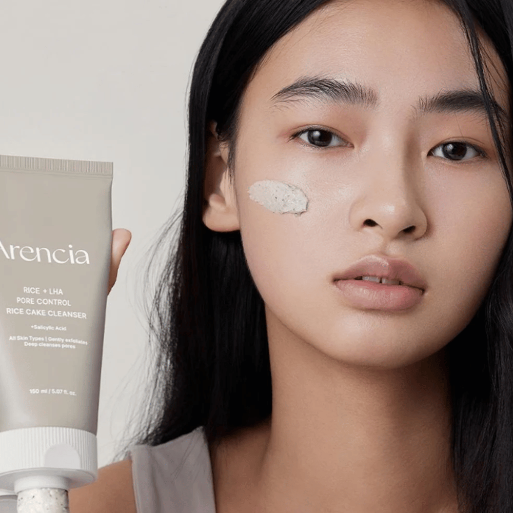 Modell som håller Arencia Rice + LHA Pore Control Rice Cake Cleanser med applicerad produkt på kinden, illustrerar mild men effektiv porrengöring för daglig användning.