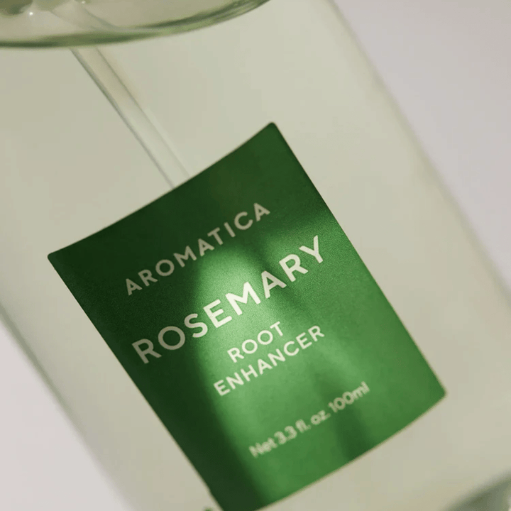 Detaljbild av etiketten på AROMATICA Rosemary Root Enhancer. Den gröna etiketten och den transparenta flaskan framhäver produktens rena och minimalistiska utseende.