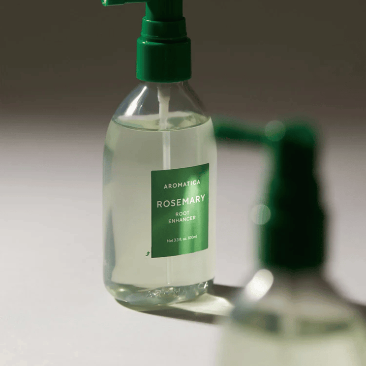 Närbild på AROMATICA Rosemary Root Enhancer med grönt applikatormunstycke. Bilden fokuserar på flaskans design och den precisa appliceringen direkt mot hårbotten.