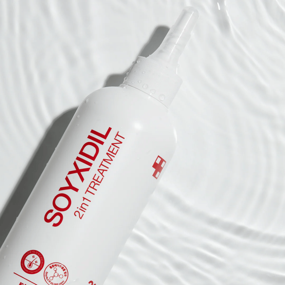 Flaska av Medicube Soyxidil 2in1 Treatment ligger på vågig vattenyta, vilket symboliserar fuktgivande och uppfriskande vård.
