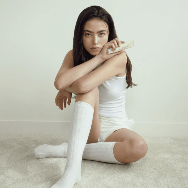 Lifestylebild med modell som håller produkten i en ljus och minimalistisk miljö. Bilden förmedlar en ren, naturlig och lugn hudvårdskänsla kopplad till glow och brightening-effekt.