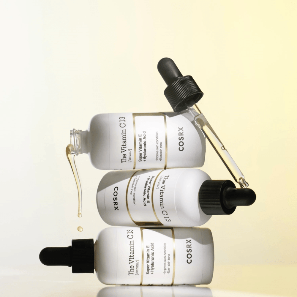 COSRX The Vitamin C 13 Serum med vitamin E och hyaluronsyra, tre flaskor med pipett och droppar av C-vitaminserum mot ojämn hudton och lyster.