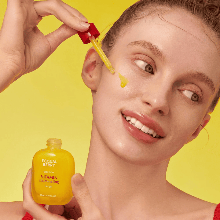Leende kvinna applicerar Equal Berry Vitamin Illuminating Serum med en pipett. Frisk och strålande hud mot en livlig gul bakgrund som matchar serumets färg.
