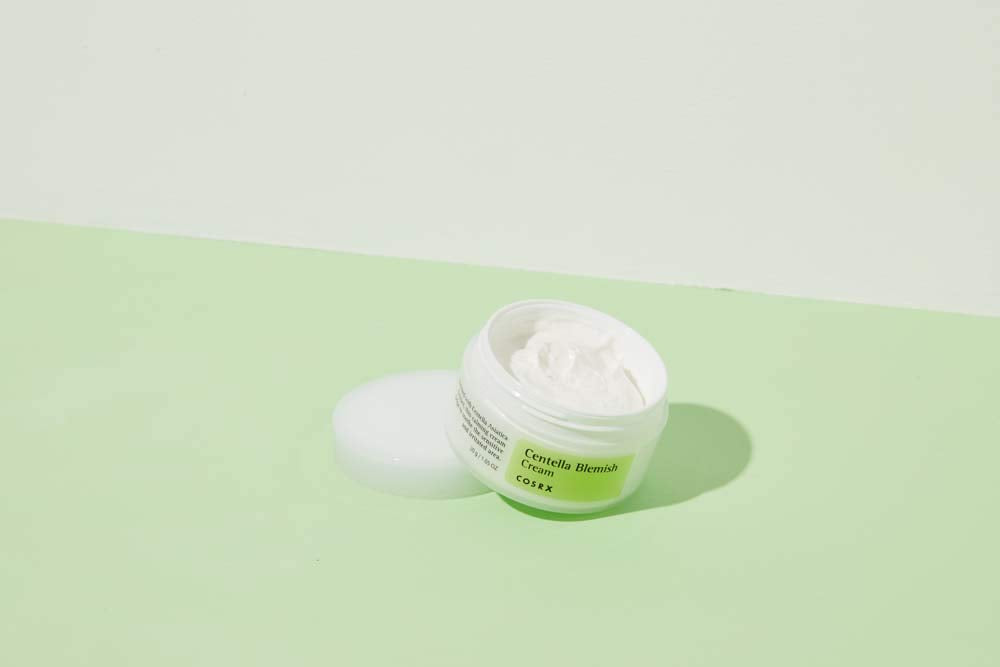En burk COSRX Centella Blemish Cream 30ml som sitter på en grön yta.