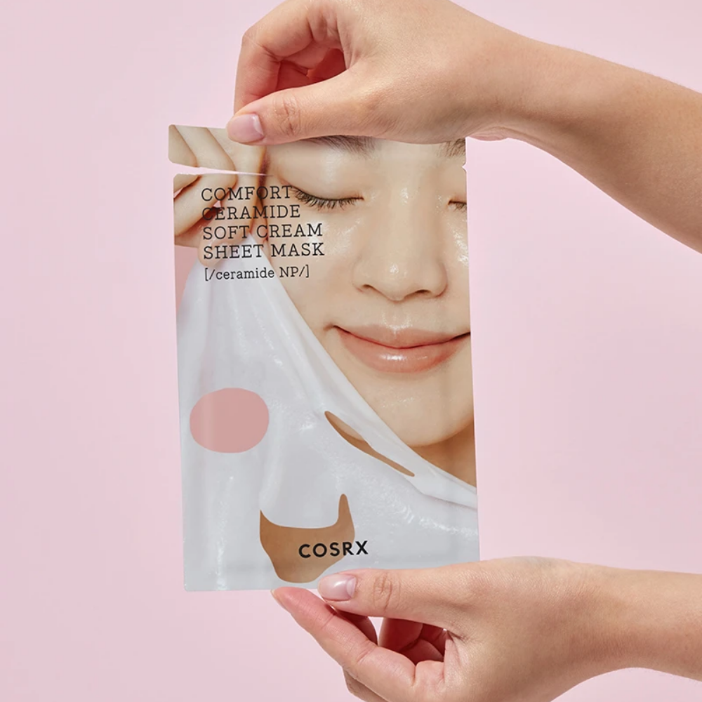 En hand som håller i en COSRX Balancium Comfort Ceramide Soft Cream Sheet Mask för återfuktning av huden.