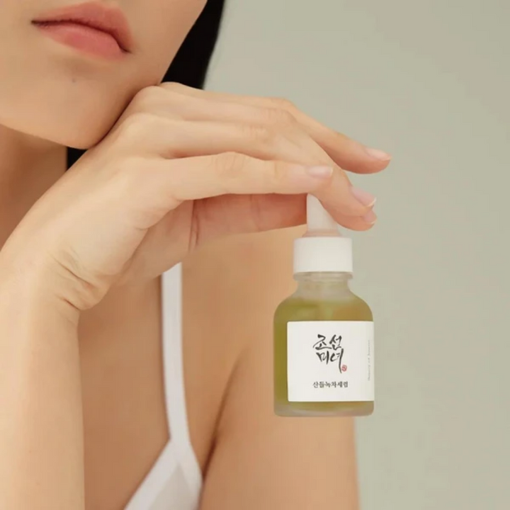 En kvinna som håller i en flaska Beauty of Joseon Calming Serum 30ml med panthenol för hudvård.
