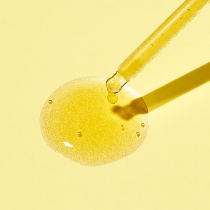 En droppe vätska på en gul bakgrund, med MISSHAs Vita C Plus Spot Correcting & Firming Ampoule.